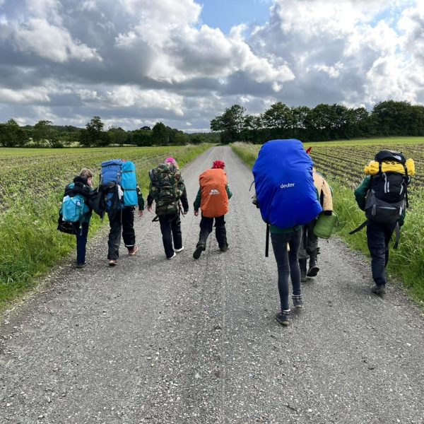 To spejderledere viser en færdselstavle for en gruppe børn