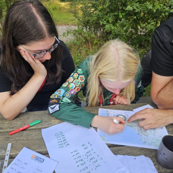 To spejderledere viser en færdselstavle for en gruppe børn
